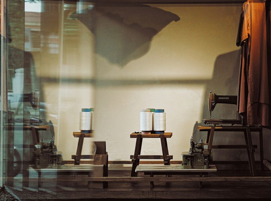 Three spools of thread on wooden stools in shop window.
